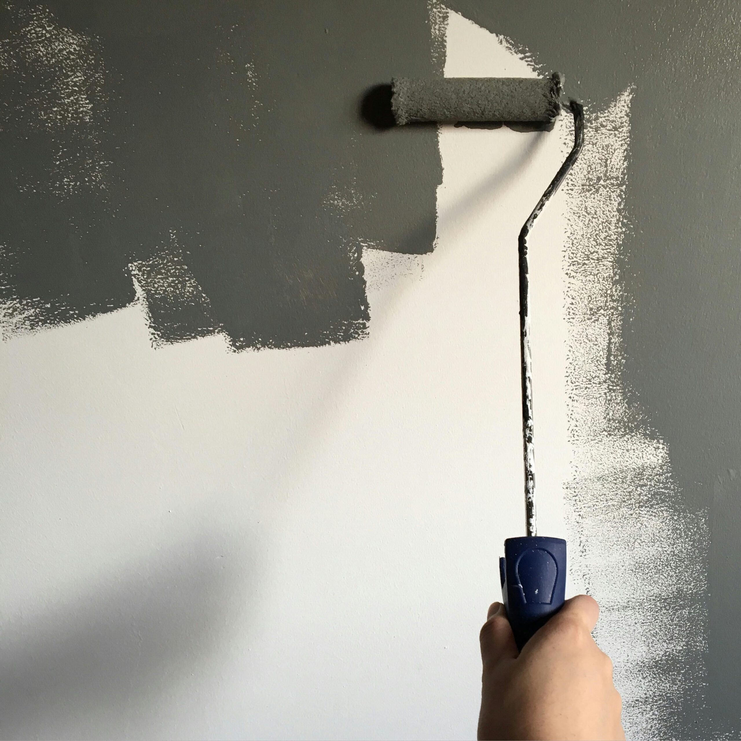Pintando una pared con un rodillo de color gris
