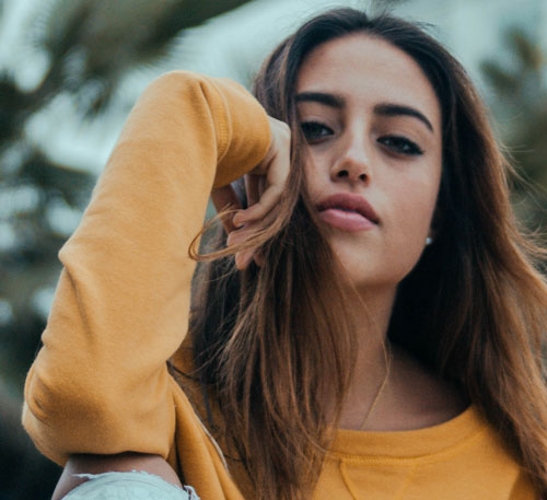 Mujer mirando a cámara con suéter naranja