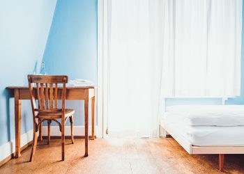 Dormitorio muy iluminado con mesa, silla y cama